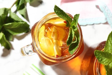 Refreshing iced peach tea with mint in mason jars on table, flat lay