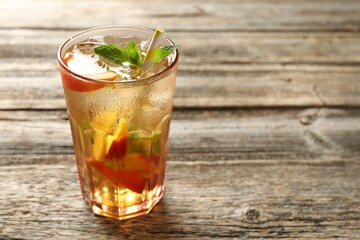 Refreshing iced peach tea in glass on wooden table, closeup. Space for text