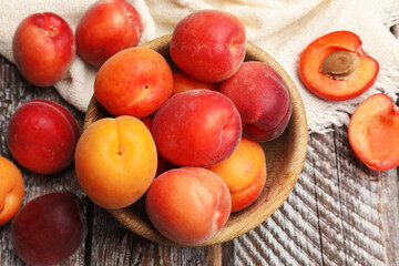 Fresh ripe apricots in bowl on wooden table, flat lay