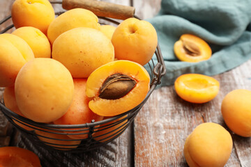 Fresh ripe apricots in metal basket on wooden table, closeup