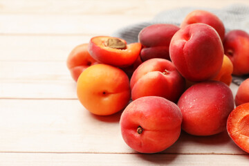 Fresh ripe apricots on light wooden table, closeup. Space for text