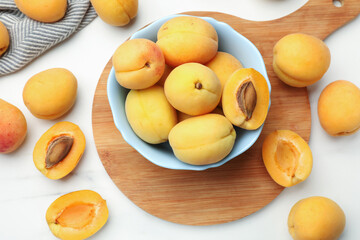 Fresh ripe apricots in bowl on white marble table, flat lay