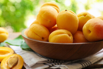 Yummy ripe apricots in bowl on table outdoors, closeup