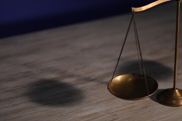 Scales of justice on wooden table, closeup. Space for text