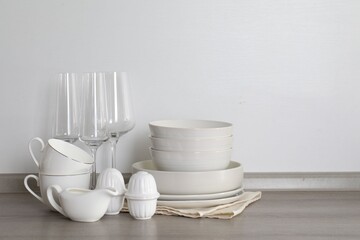 Different clean white dishware and glasses on counter in kitchen