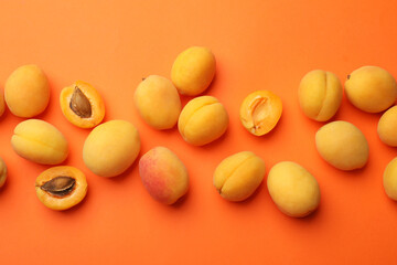 Many fresh apricots on orange background, flat lay