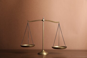 Golden scales of justice on wooden table