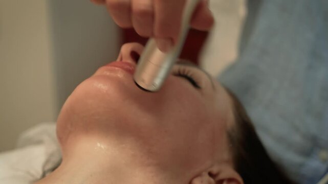 Woman benefiting from revitalizing facial treatment by experienced therapist in wellness spa. Ultrasonic Facial Massage, Microcurrent Therapy. Facial enhancement, epidermis care, anti-aging skin
