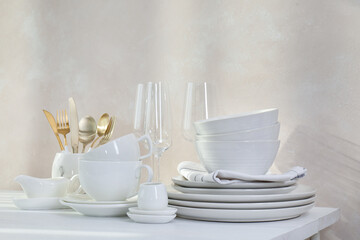 Different clean white dishware and glasses on counter in kitchen
