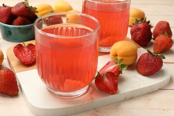 Tasty compot in glasses, fresh strawberries and apricots on wooden table, closeup