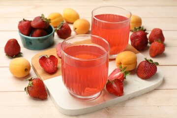 Tasty compot in glasses, fresh strawberries and apricots on wooden table, closeup