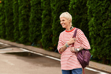 Fototapeta premium Stylish young woman enjoying a sunny day in the park with vibrant greenery around
