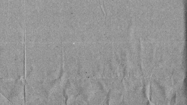 Grey kraft paper noise texture 4K stop motion video. Aged old page overlay effect background loop animation. Vintage paper texture with crease, stain, grain, dust particles. Empty animated backdrop