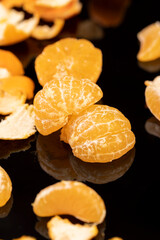 the reflection of an orange citrus tangerine in a black mirror surface close up, a peeled and juicy tangerine on a black mirror