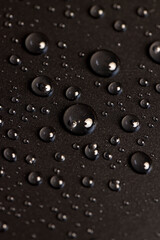 a black surface covered with water droplets, details of the wet part of an object made of black plastic