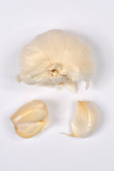 A garlic bulb, with some cloves separated from it, arranged on a simple white background