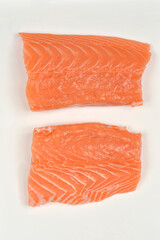 Two fresh, raw salmon fillet portions with their vibrant orange flesh, placed side by side on a clean white background