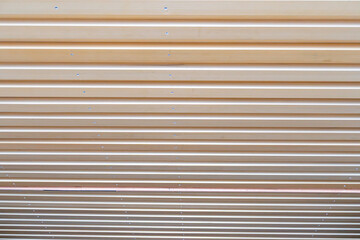 Fototapeta premium Top-down view of a wooden slatted structure, secured with screws at regular intervals, set against a neutral background The color palette primarily features natural brown tones