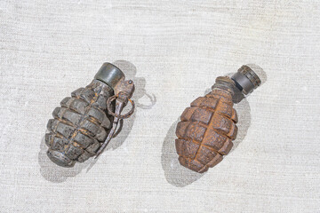 Summary Two rusted grenades on a worn tablecloth Rough texture, visible detail, loop at one end,...