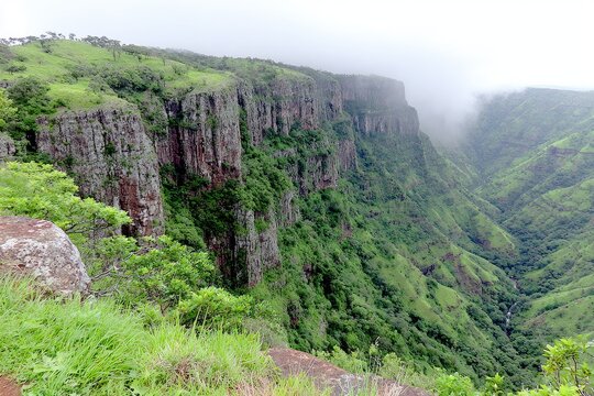 Steep cliffs form a valley, lush green vegetation - Powered by Adobe
