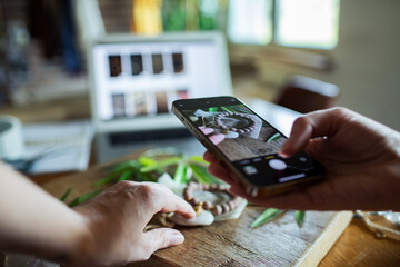 Woman photographing handmade jewelry products for online shop at home