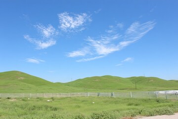 Rolling hills, bright green grass, clear blue sky with wispy clouds