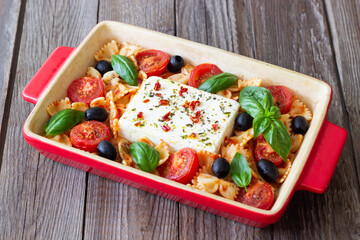 Baked feta cheese with farfalle pasta, basil, tomatoes and olives. Healthy food. Vegetarian food.