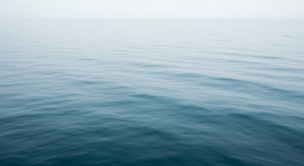 Obraz premium Calm, serene ocean surface fading into a misty, overcast sky.