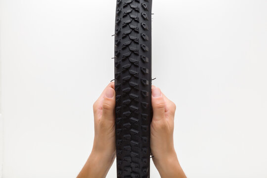 Young man hands holding and showing new bicycle tire tread on light gray background. Closeup. Point of view shot.