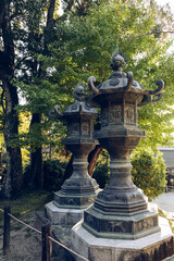 Obraz premium Two bronze lantern columns with ornate decorations at Kasuga Taisha Shrine Nara Japan surrounded by green foliage in warm golden hour light creating peaceful mood