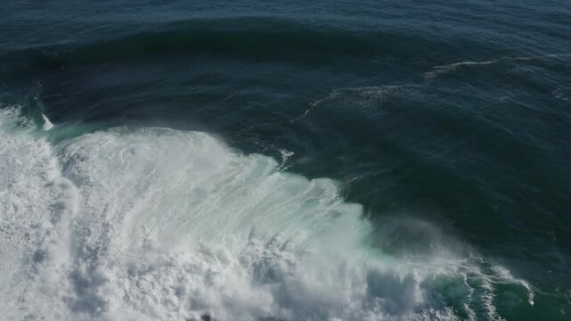 A large ocean wave curls and breaks over an exposed reef, exploding into the air. Captured from high above during a storm swell on the East Coast of Australia.