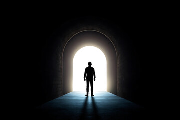 Man silhouettes against bright light in arched tunnel, facing future challenges