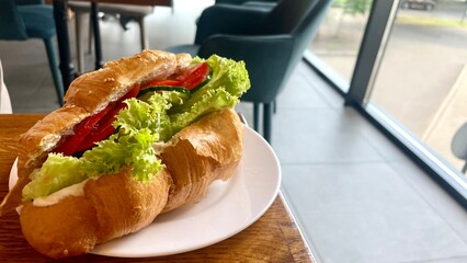 Croissant with vegetable filling and sesame seeds on a plate in a cafe