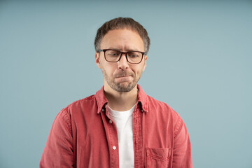 Upset thoughtful man sadly looks down biting lips with excitement frowning forehead wearing eyeglasses isolated background. Stressed nervous middle aged male worried thinking about troubles solutions.