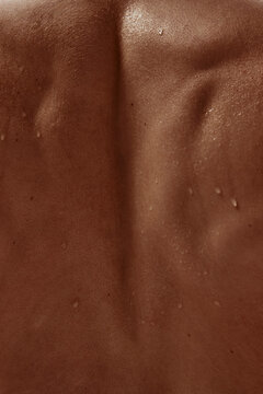 Back view of muscular male torso with visible sweat droplets and skin pores. Concept of male spa promotion, body identity series, wellness poster design, and mental health support.