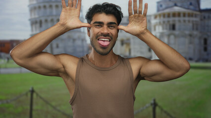 Man in brown tank top shows middle finger gesture at pisa tower building; defiance rebellion...