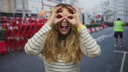Fototapeta premium Woman hair peeking street captures blonde young model at construction barricade in city happy pose.