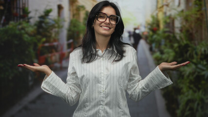 Woman shrugs with hand palms up on busy outdoor street lined with plants and buildings; inner...