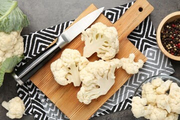 Fresh raw cauliflower florets, spices and knife on grey table, flat lay