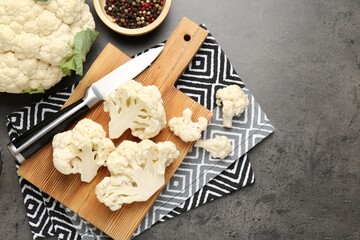 Fresh raw cauliflower florets, spices and knife on grey table, flat lay. Space for text