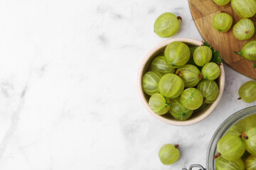 Fresh green gooseberries on white marble table, flat lay. Space for text