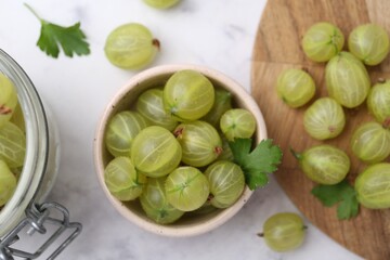 Fresh green gooseberries on white marble table, flat lay