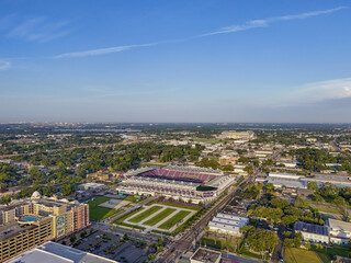 Orlando, United States - 21 July 2025: Aerial view of Camping World Stadium, a vibrant splash of color amidst the city's green canopy, under a vast, clear sky.
