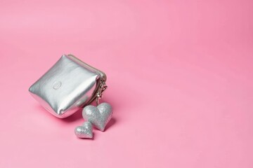 A Silver Zippered Pouch with Glittering Heart Charms on a Pink Background