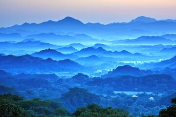 Fototapeta premium Misty mountain range panorama in soft blue tones