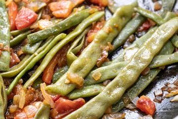 Fried green beans with tomato and onion pieces. Tasty meal with french bean on dinner or lunch on the pan