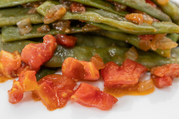 Fried green beans with tomato and onion pieces. Tasty meal with french bean on dinner or lunch on the white background