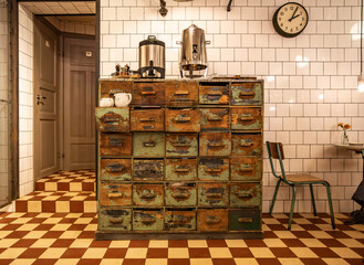 Interior of a retro café with a distressed vintage drawer cabinet, metal tea urns, tiled walls,...
