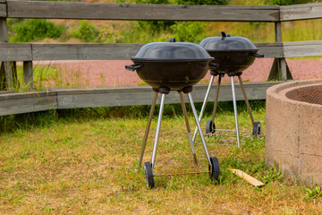 Classic kettle BBQ grill outdoors in nature, round and black with a domed lid, perfect for charcoal...