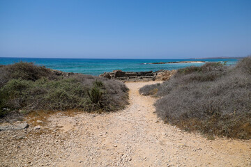 Sandy path to the seashore. Azure water of the Mediterranean Sea. Vacation, travel in the vicinity of Ayia Napa, Republic of Cyprus